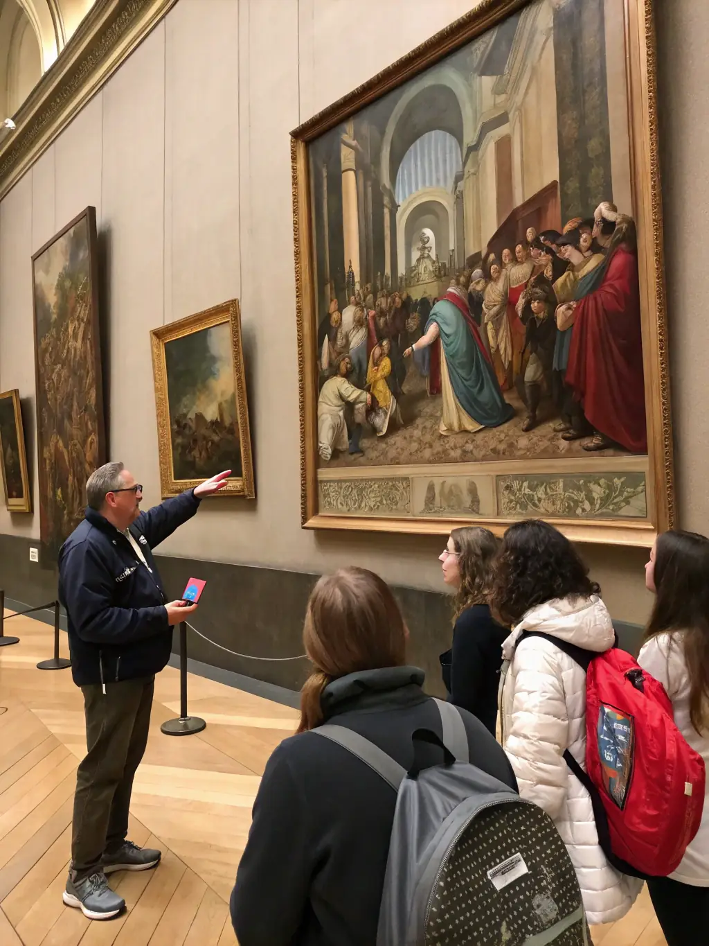 A group of visitors attentively listening to a museum guide during a tour of the MUSEE DEPARTEMENTAL DE L'ECOLE PUBLIQUE's educational exhibitions, surrounded by historical displays and artifacts.